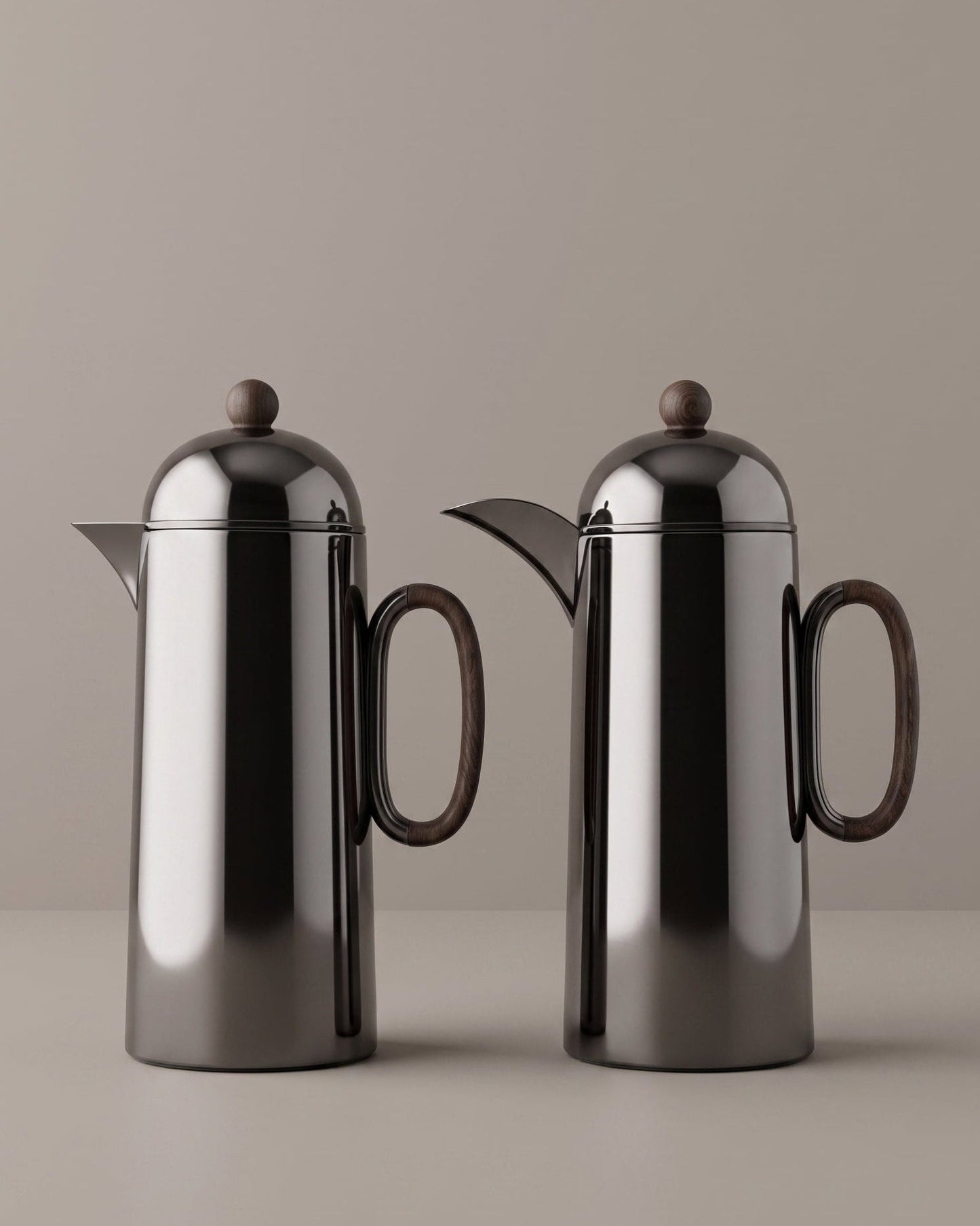 Two black coffee pots on a beige background