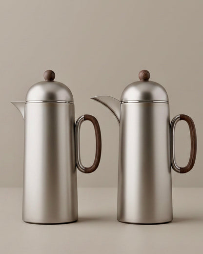 Two silver titanium thermoses with wooden handles on a beige background